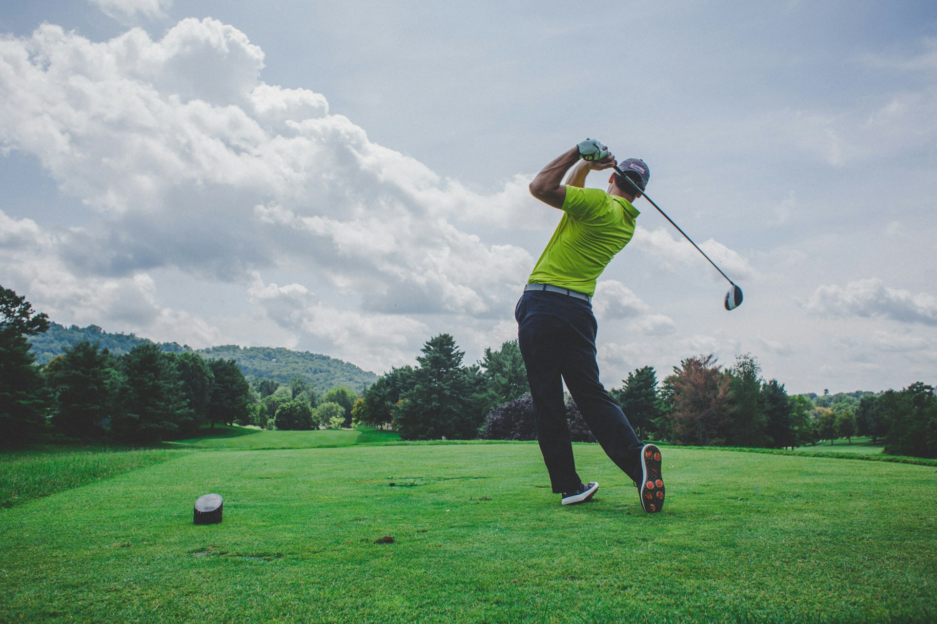 A golfer finishing a driver swing on an open tee box